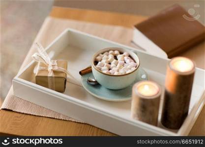 holidays and still life concept - hot chocolate with marshmallow, christmas gift and candles on table. hot chocolate, christmas gift and candles on table