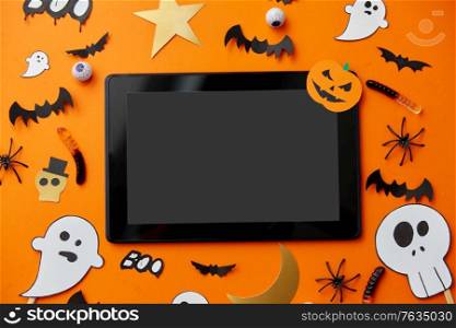 holidays and technology concept - tablet pc computer with halloween party props and decorations. tablet pc, halloween party props and decorations