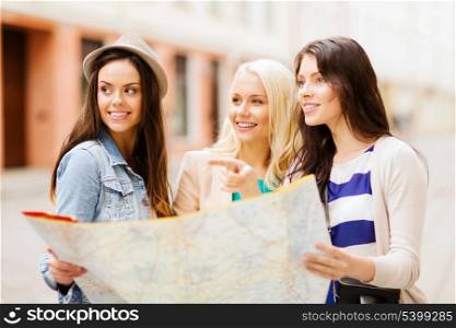 holidays and tourism concept - beautiful girls looking for direction in the city
