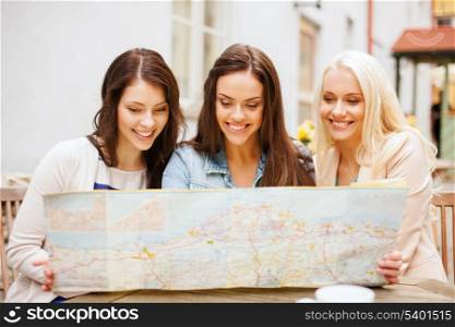 holidays and tourism concept - beautiful girls looking into tourist map in the city