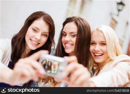 holidays and tourism concept - beautiful girls taking picture in the city