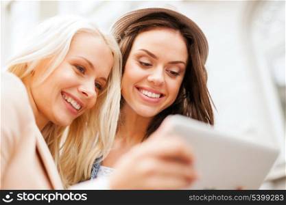 holidays and tourism concept - beautiful girls toursits looking into tablet pc in the city