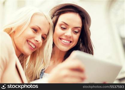 holidays and tourism concept - beautiful girls toursits looking into tablet pc in the city