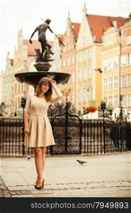 Holidays and tourism concept. Full length pretty woman in elegant dress outdoor on the street of old town european city Gdansk Danzig Neptune fountain Poland
