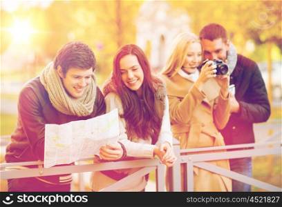 holidays and tourism concept - group of friends or couples with tourist map and camera in autumn park. couples with tourist map and camera in autumn park