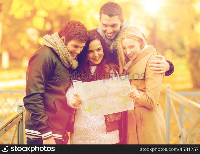 holidays and tourism concept - group of friends or couples with tourist map in autumn park. couples with tourist map in autumn park