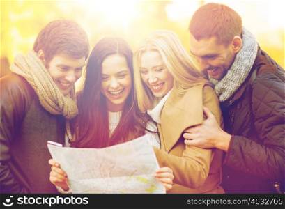 holidays and tourism concept - group of friends or couples with tourist map in autumn park. couples with tourist map in autumn park
