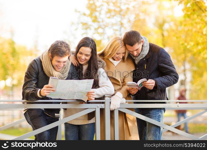 holidays and tourism concept - group of friends or couples with tourist map in autumn park