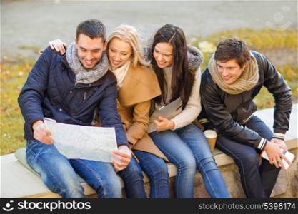 holidays and tourism concept - group of friends or couples with tourist map in autumn park