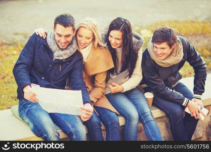 holidays and tourism concept - group of friends or couples with tourist map in autumn park