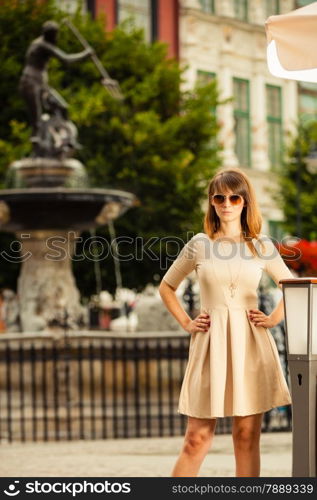 Holidays and tourism concept. pretty woman in elegant dress outdoor on the street of the old town european city Gdansk Danzig Neptune fountain Poland
