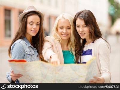 holidays and tourism concept - three beautiful girls looking into tourist map in the city