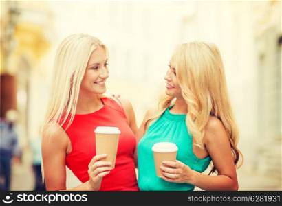 holidays and tourism, friends and blonde girls concept - two beautiful women with takeaway coffee cups in the city
