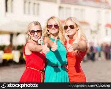 holidays and tourism, friends, hen party, blonde girls concept - three beautiful women in the city showing thumbs up