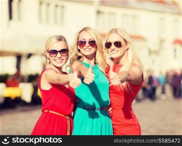 holidays and tourism, friends, hen party, blonde girls concept - three beautiful women in the city showing thumbs up