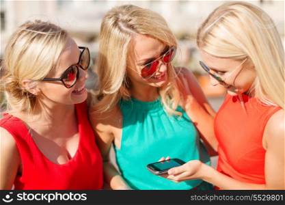 holidays and tourism, modern technology concept - beautiful blonde girls with smartphone in the city
