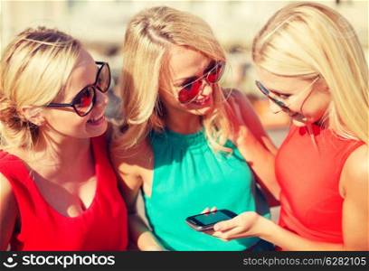 holidays and tourism, modern technology concept - beautiful blonde girls with smartphone in the city