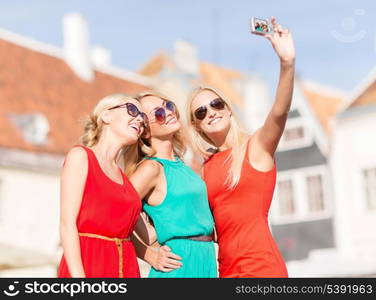 holidays and tourism, modern technology concept - beautiful girls taking picture in the city