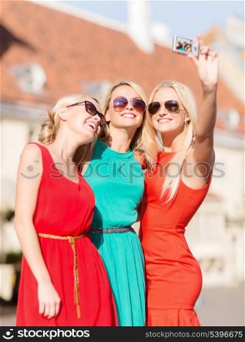 holidays and tourism, modern technology concept - beautiful girls taking picture in the city