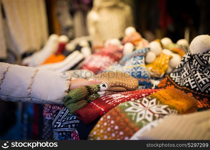 holidays and winter clothes concept - close up of woman buying woolen mittens at christmas market. woman buying woolen mittens at christmas market