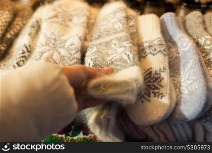 holidays and winter clothes concept - close up of woman buying woolen mittens at christmas market. woman buying woolen mittens at christmas market