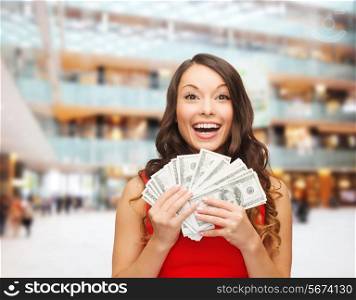 holidays, banking, winning and people concept - smiling woman in red dress with us dollar money over shopping centre background