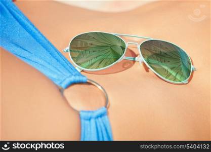 holidays, beach and shades advertisement concept - sunglasses laying on woman body