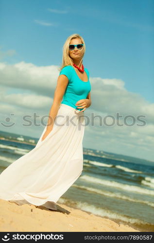 Holidays, beauty and summer fashion concept. Attractive blonde girl in full length walking on beach. Young woman relaxing on the sea shore.