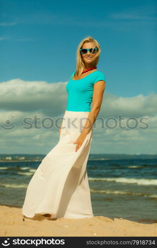 Holidays, beauty and summer fashion concept. Attractive blonde girl in full length walking on beach. Young woman relaxing on the sea shore.