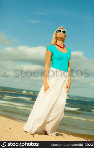 Holidays, beauty and summer fashion concept. Attractive blonde girl in full length walking on beach. Young woman relaxing on the sea shore.