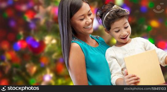 holidays, birthday, family, childhood and people concept - happy mother and little girl with gift over lights background