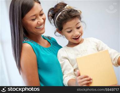 holidays, birthday family, childhood and people concept - happy mother and little girl with gift box at home