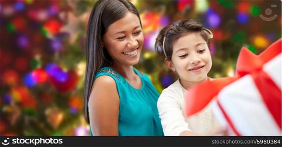 holidays, birthday, family, childhood and people concept - happy mother and little girl with gift box over lights background