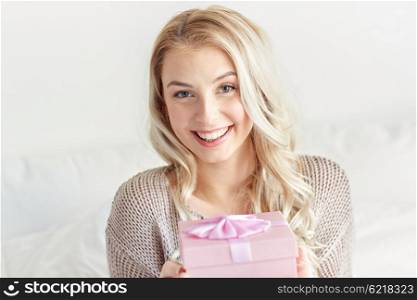 holidays, birthday, morning and people concept - happy young woman gift box or present at home