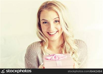 holidays, birthday, morning and people concept - happy young woman gift box or present at home. happy young woman with gift box at home