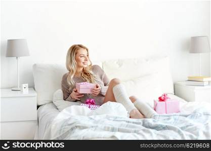 holidays, birthday, morning and people concept - happy young woman gift boxes or presents in bed at home bedroom