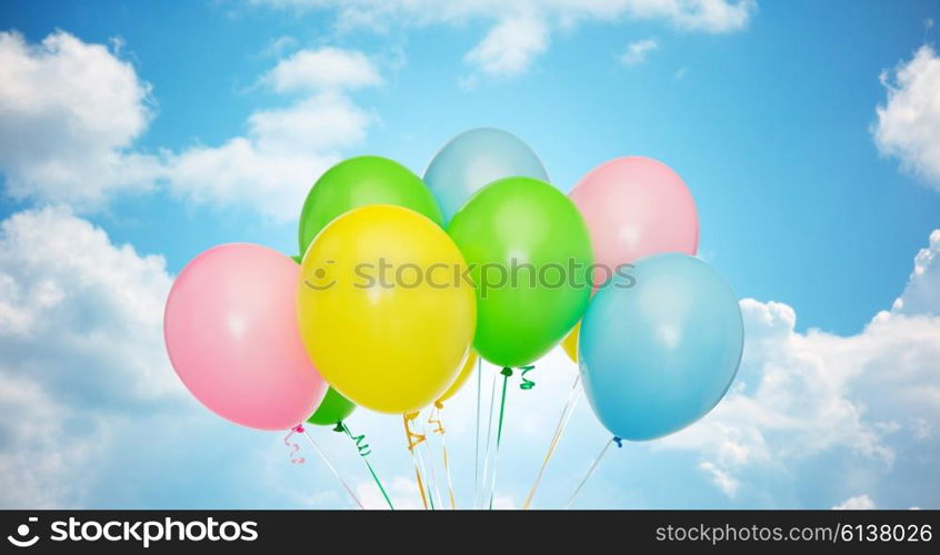 holidays, birthday, party and decoration concept - bunch of inflated colorful helium balloons over blue sky and clouds background