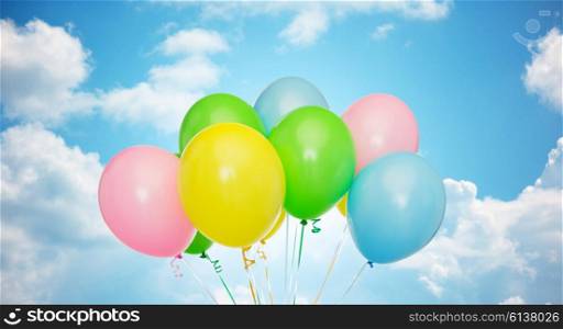 holidays, birthday, party and decoration concept - bunch of inflated colorful helium balloons over blue sky and clouds background