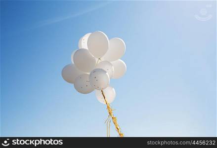 holidays, birthday, party and decoration concept - close up of inflated white helium balloons in blue sky
