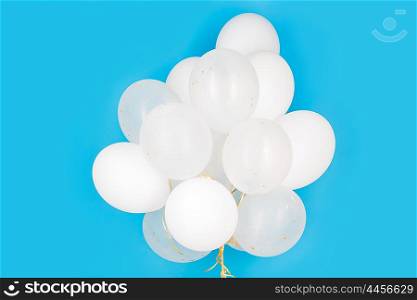 holidays, birthday, party and decoration concept - close up of inflated white helium balloons over blue background
