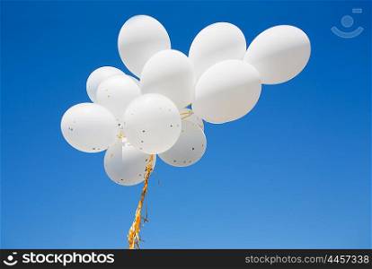 holidays, birthday, party and decoration concept - close up of inflated white helium balloons in blue sky