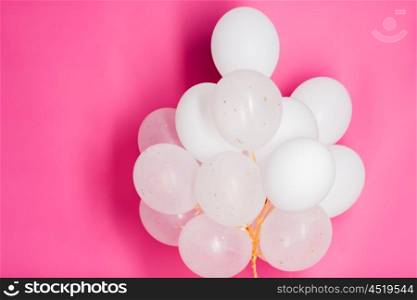 holidays, birthday, party and decoration concept - close up of inflated white helium balloons over pink background