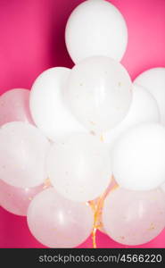 holidays, birthday, party and decoration concept - close up of inflated white helium balloons over pink background