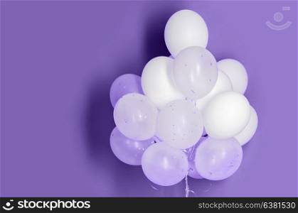 holidays, birthday, party and decoration concept - close up of inflated white helium balloons on ultra violet background. white helium balloons on ultra violet background