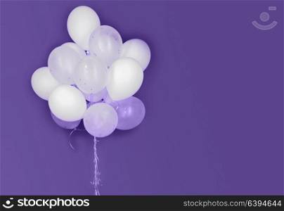holidays, birthday, party and decoration concept - close up of inflated white helium balloons on ultra violet background. white helium balloons on ultra violet background