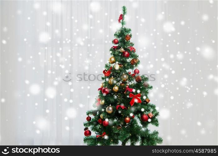 holidays, celebration and home concept - christmas tree in living room over window curtain
