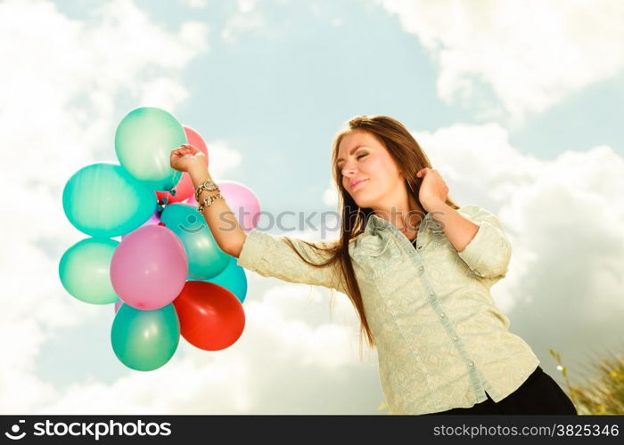 holidays, celebration and lifestyle concept - attractive woman female model holding bunch of colorful balloons outside cloudy sky background