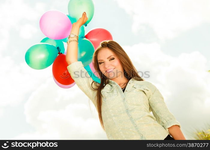 holidays, celebration and lifestyle concept - attractive woman female model holding bunch of colorful balloons outside cloudy sky background