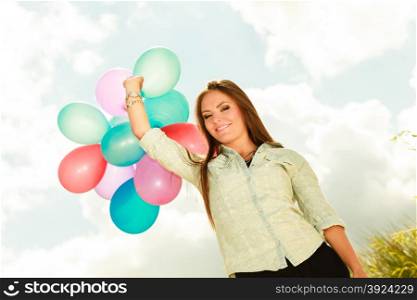 holidays, celebration and lifestyle concept - attractive woman female model holding bunch of colorful balloons outside cloudy sky background