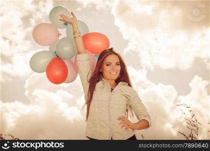 holidays, celebration and lifestyle concept - attractive woman female model holding bunch of colorful balloons outside cloudy sky background. Aged tone